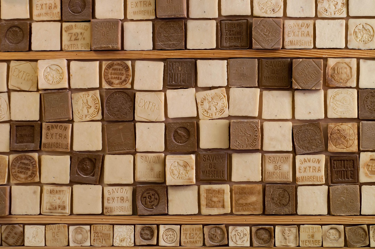 An assortment of artisan soap bars in various colors like green, pink, and yellow placed on a wooden tray