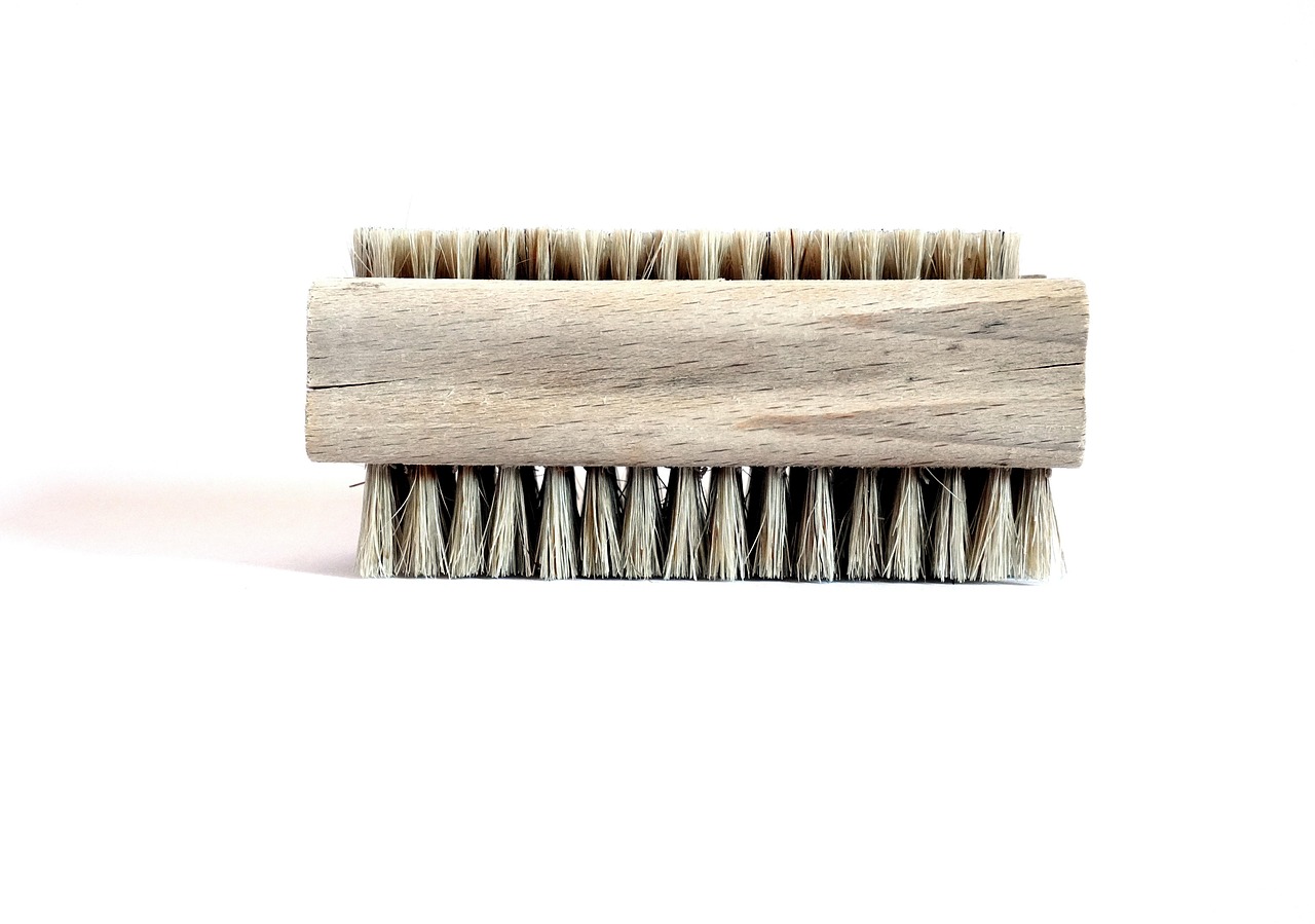 Coconut coir scrub brush being used to clean a stainless steel pan in a kitchen sink