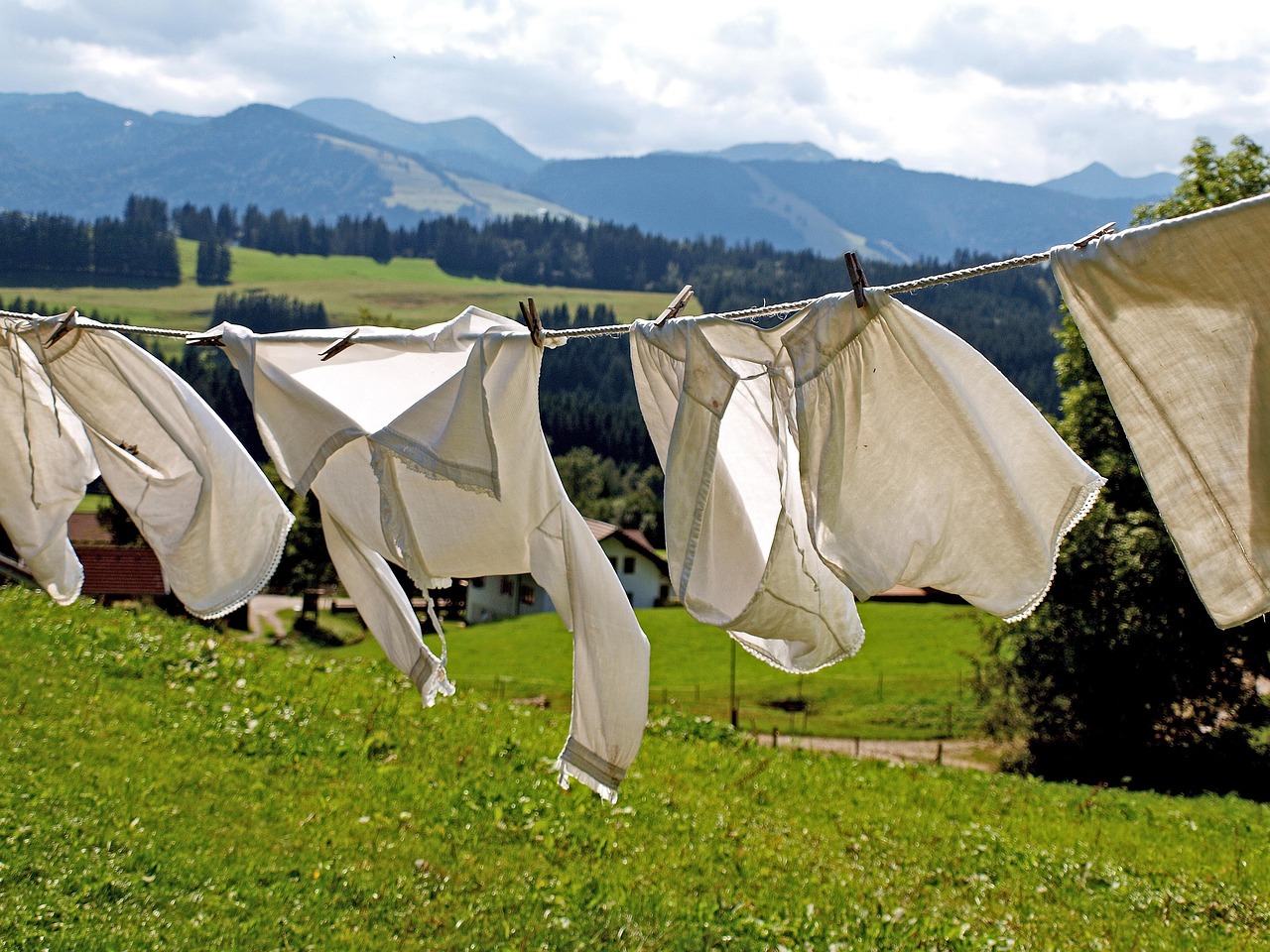 Hand-dyed wrapping paper sheets hanging from a clothesline with wooden clothespins