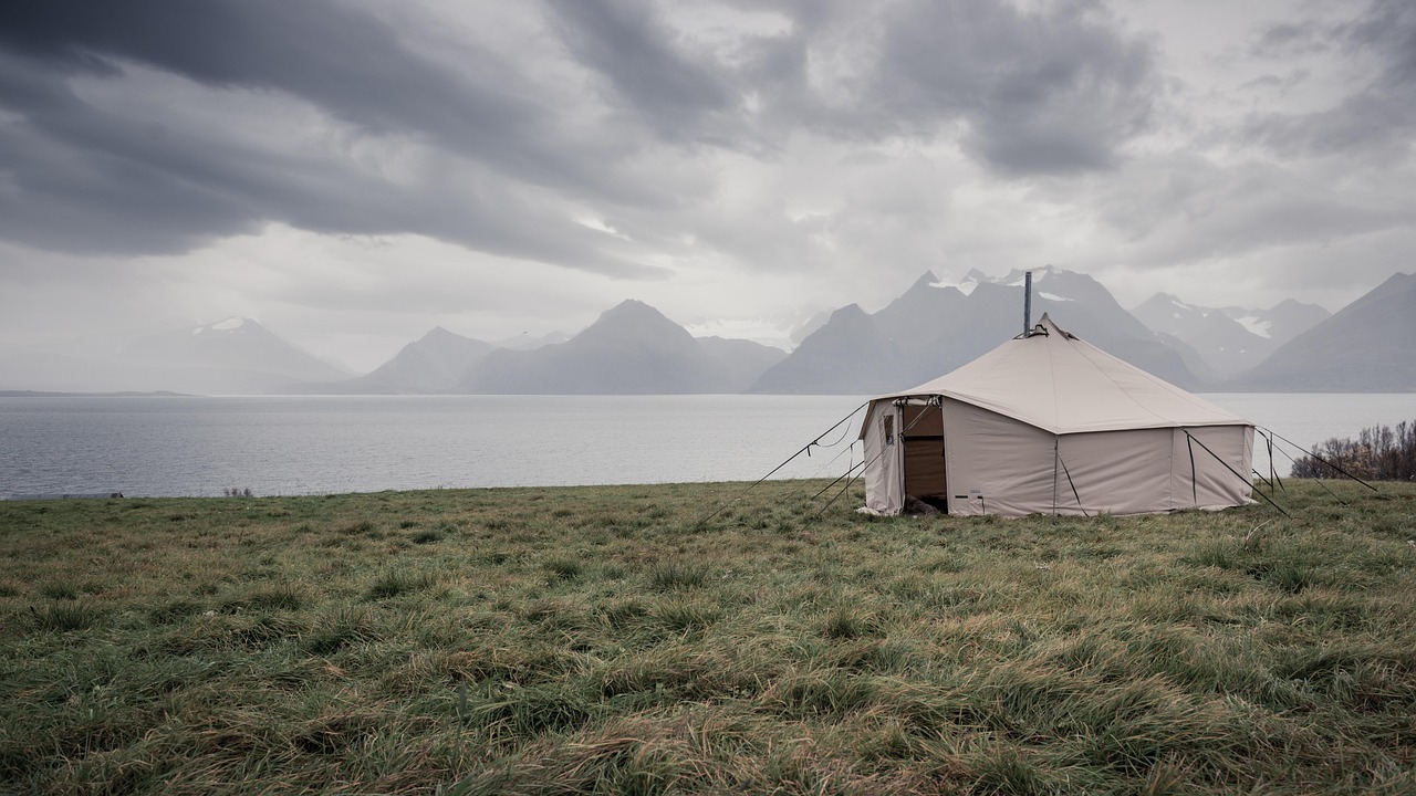A spacious glamping tent with a comfortable bed and wooden floor set in a lush forest clearing