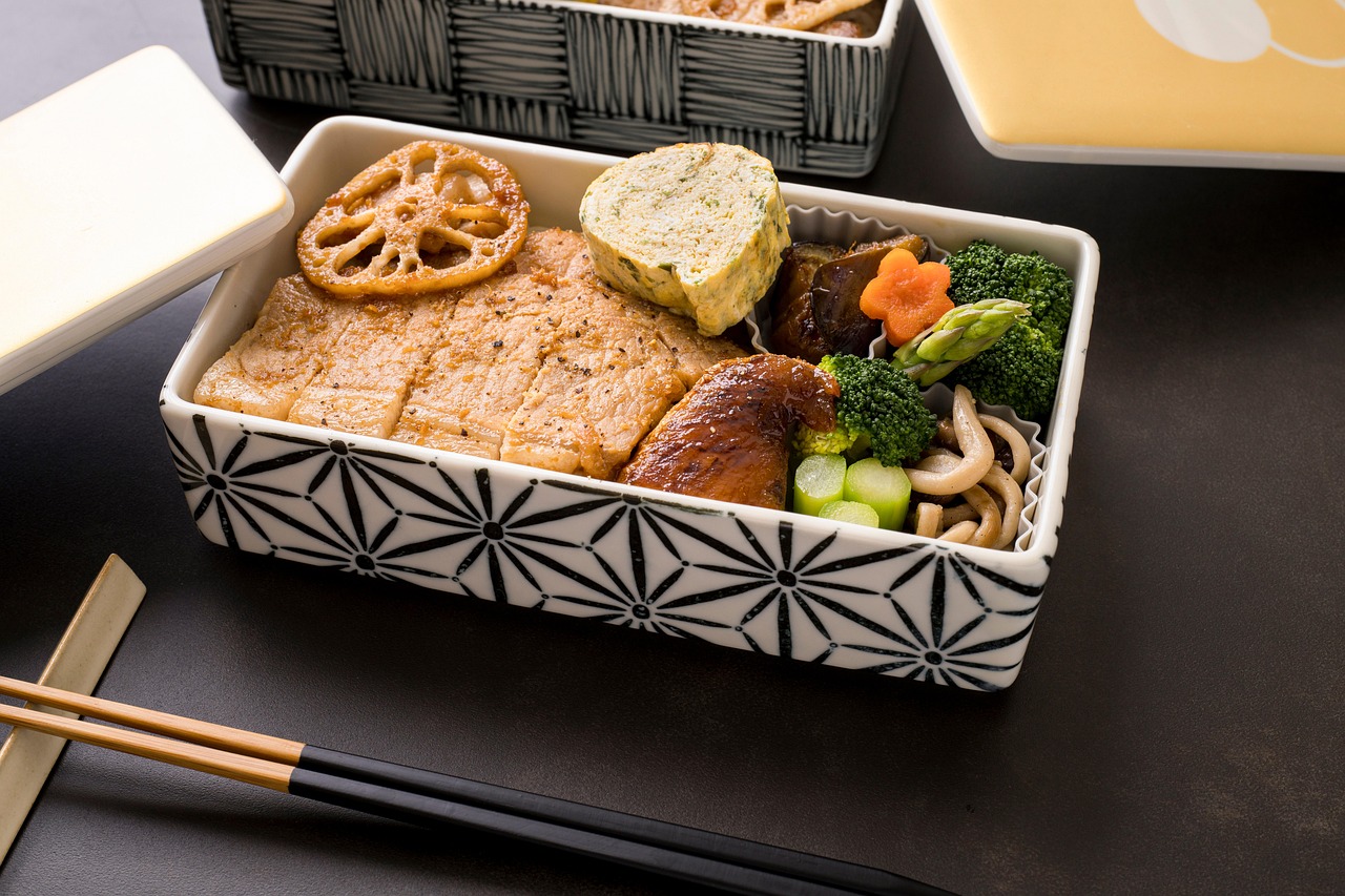 Glass bento lunch box with three compartments filled with vegetables and quinoa
