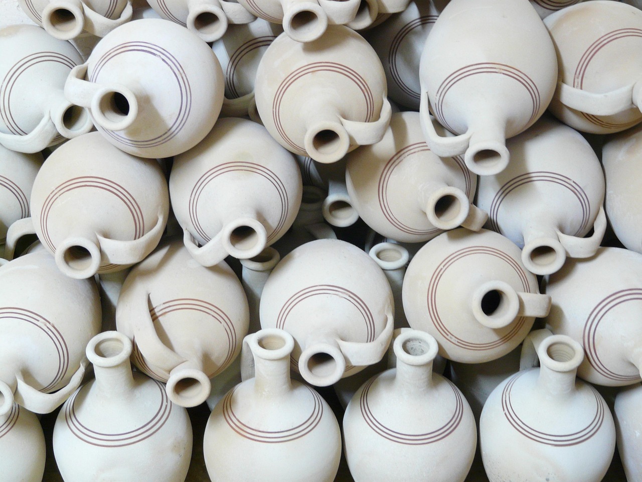 A collection of handmade ceramic planters in various shapes and glazes displayed on a shelf