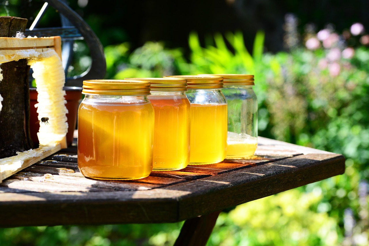 Hand holding a jar of honey showing a label that reads raw and unfiltered