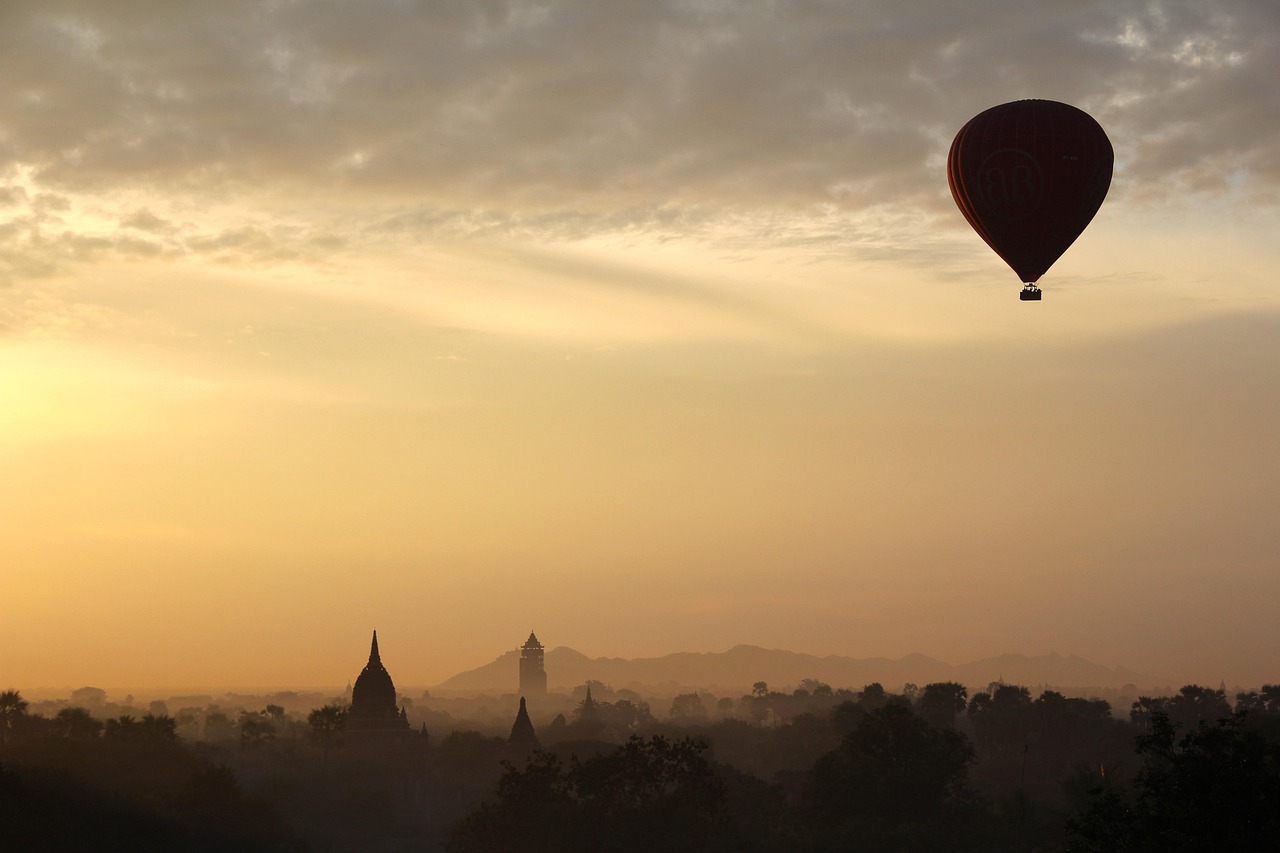 Colorful hot air balloon floating at sunrise over a green countryside