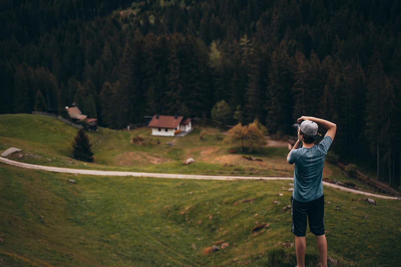 A photographer carrying a camera backpack while hiking through a scenic mountain landscape at sunrise