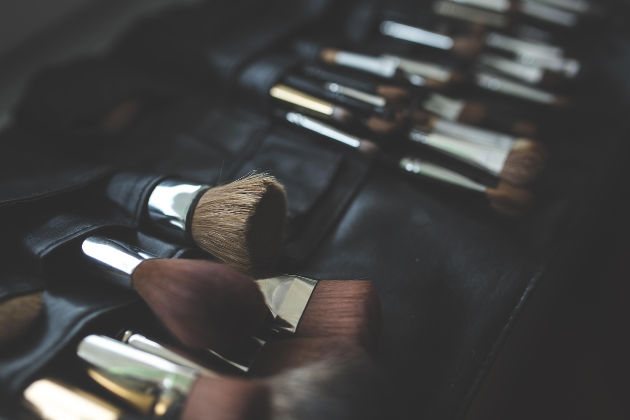 A leather care kit including a jar of conditioner and a horsehair brush on a wooden surface.