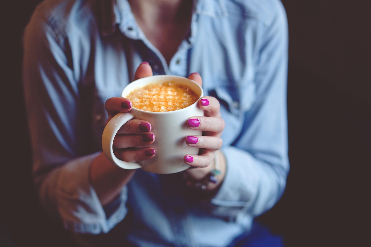 A person holding a reusable coffee cup while walking outdoors