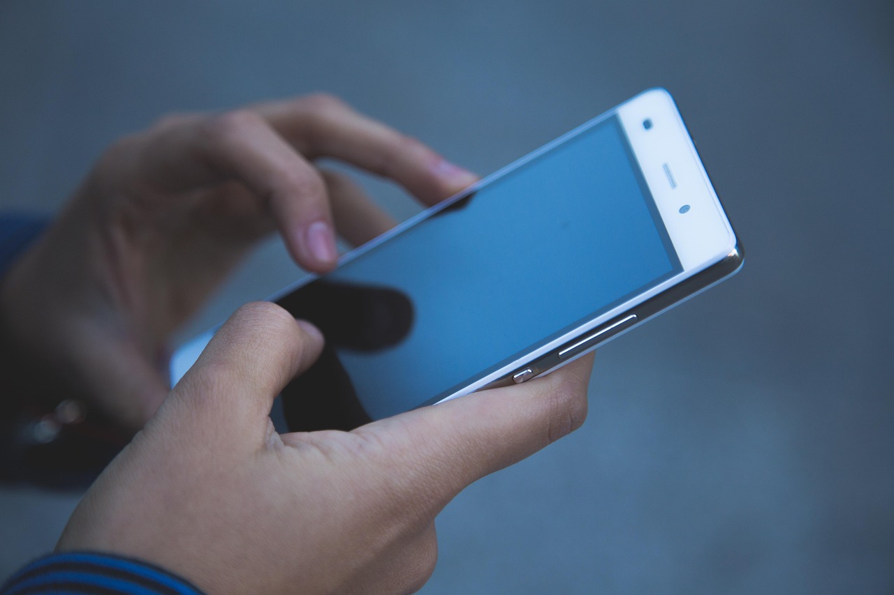 A portable solar charger unfolded on grass with a smartphone connected