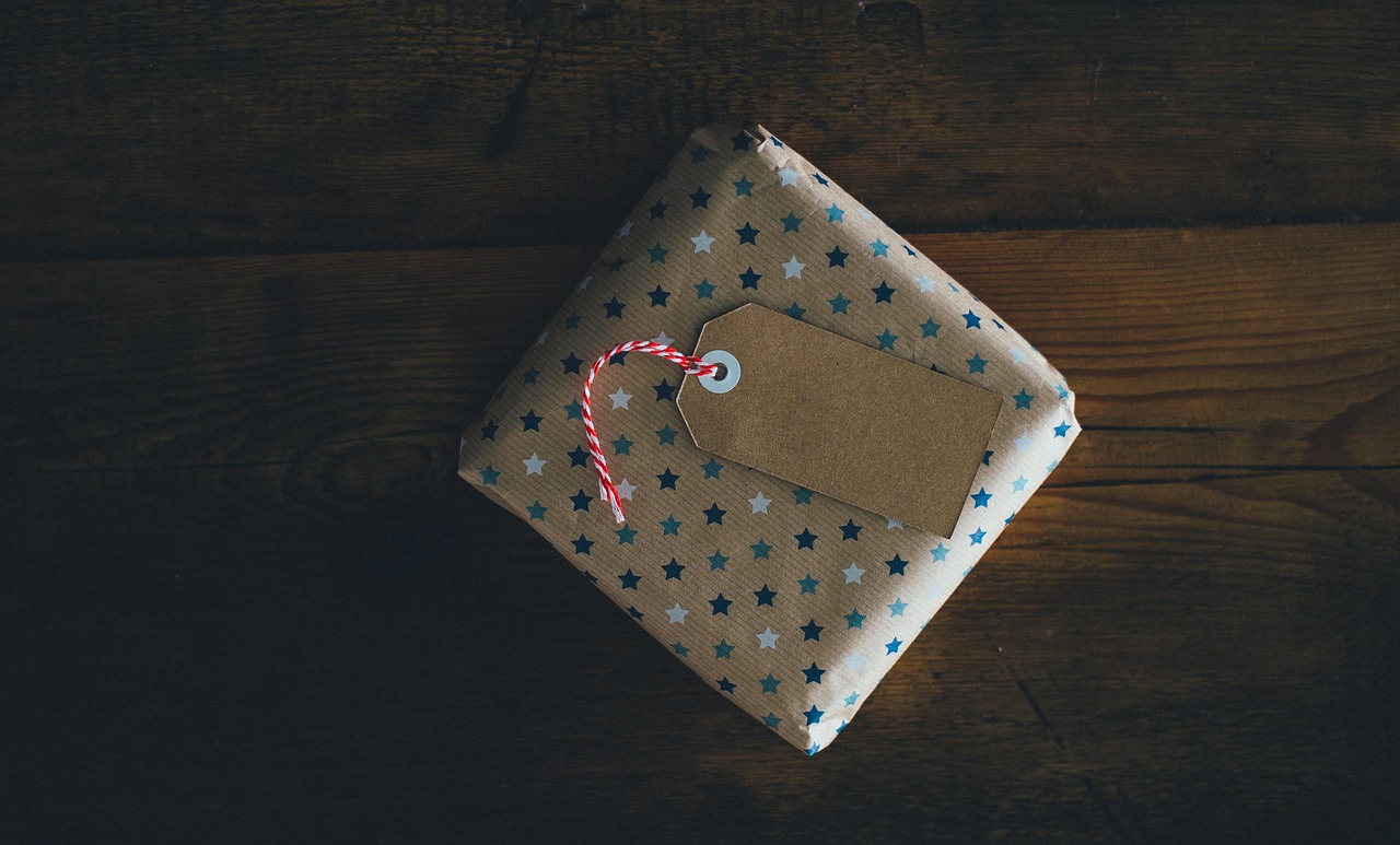 A gift wrapped in brown kraft paper with hemp twine and a sprig of rosemary