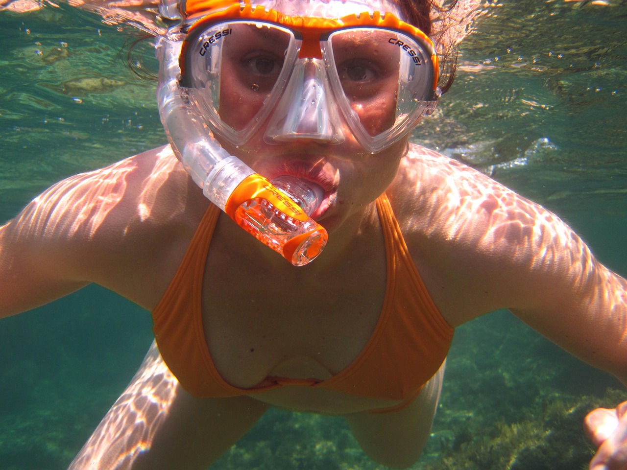 A snorkeling mask, fins, and snorkel laid out on a sandy beach