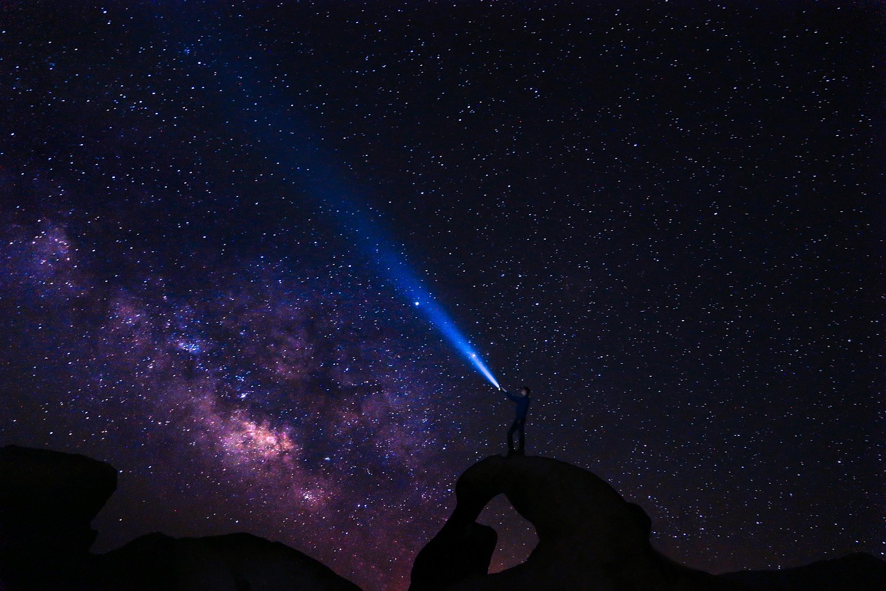 A person using a telescope under a dark night sky with visible stars