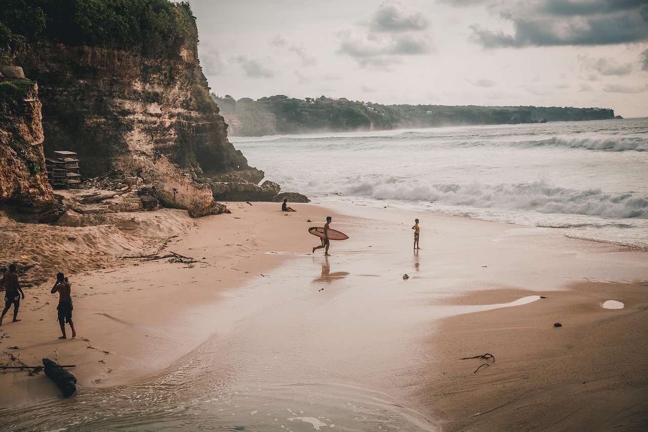 A surf lesson gift certificate placed on sand next to a surfboard and shells.