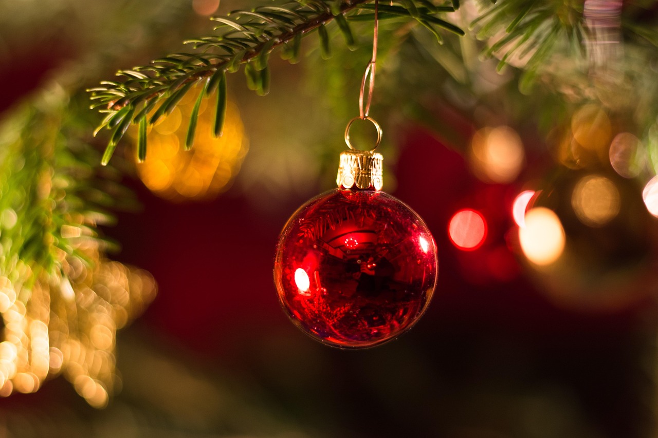 A selection of hand-painted terracotta ornaments in Mediterranean colors hanging on a Christmas tree.