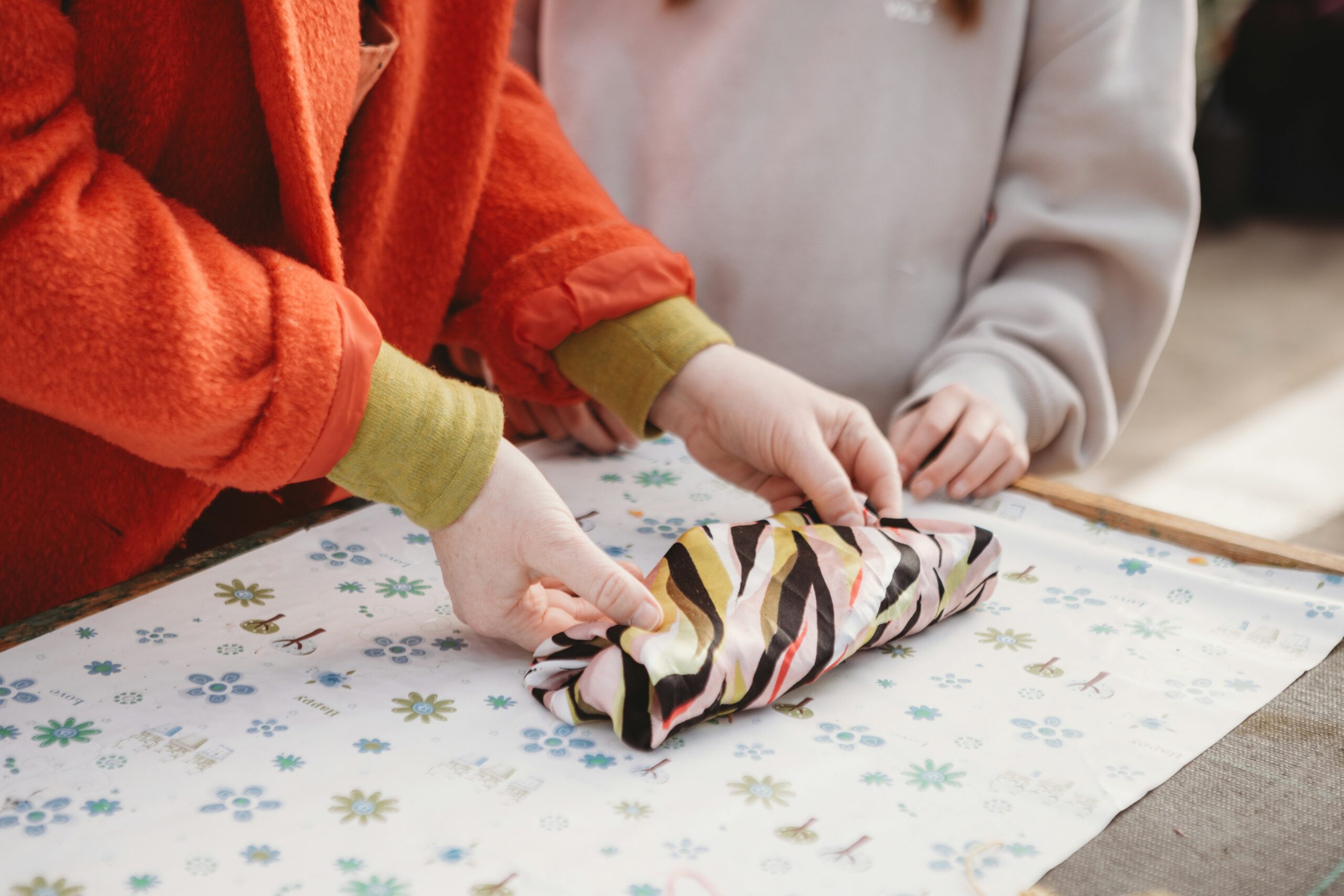 Hands wrapping an object in patterned fabric.