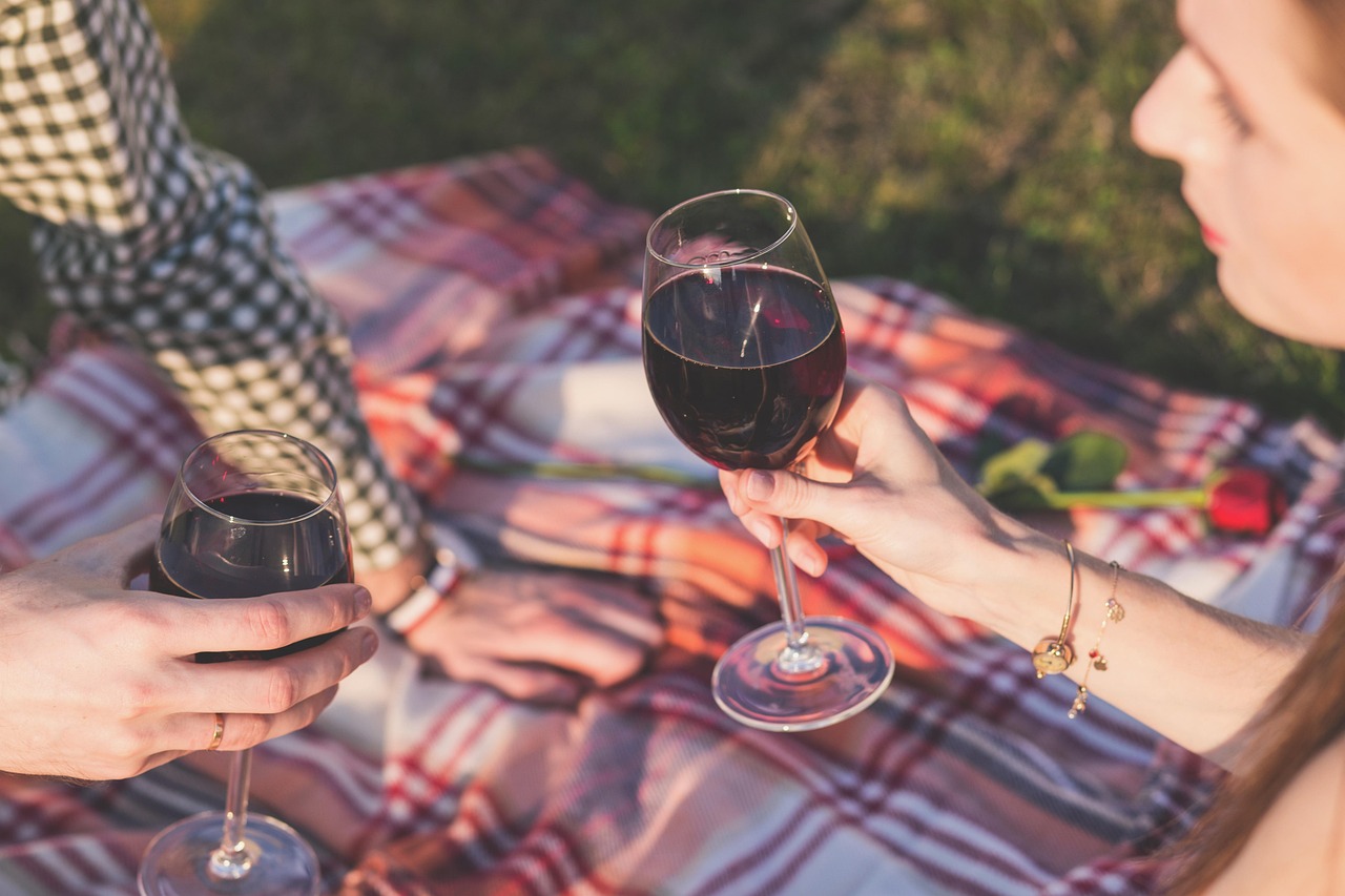 Wine accessories including a corkscrew, picnic blanket, and glasses laid out on grass