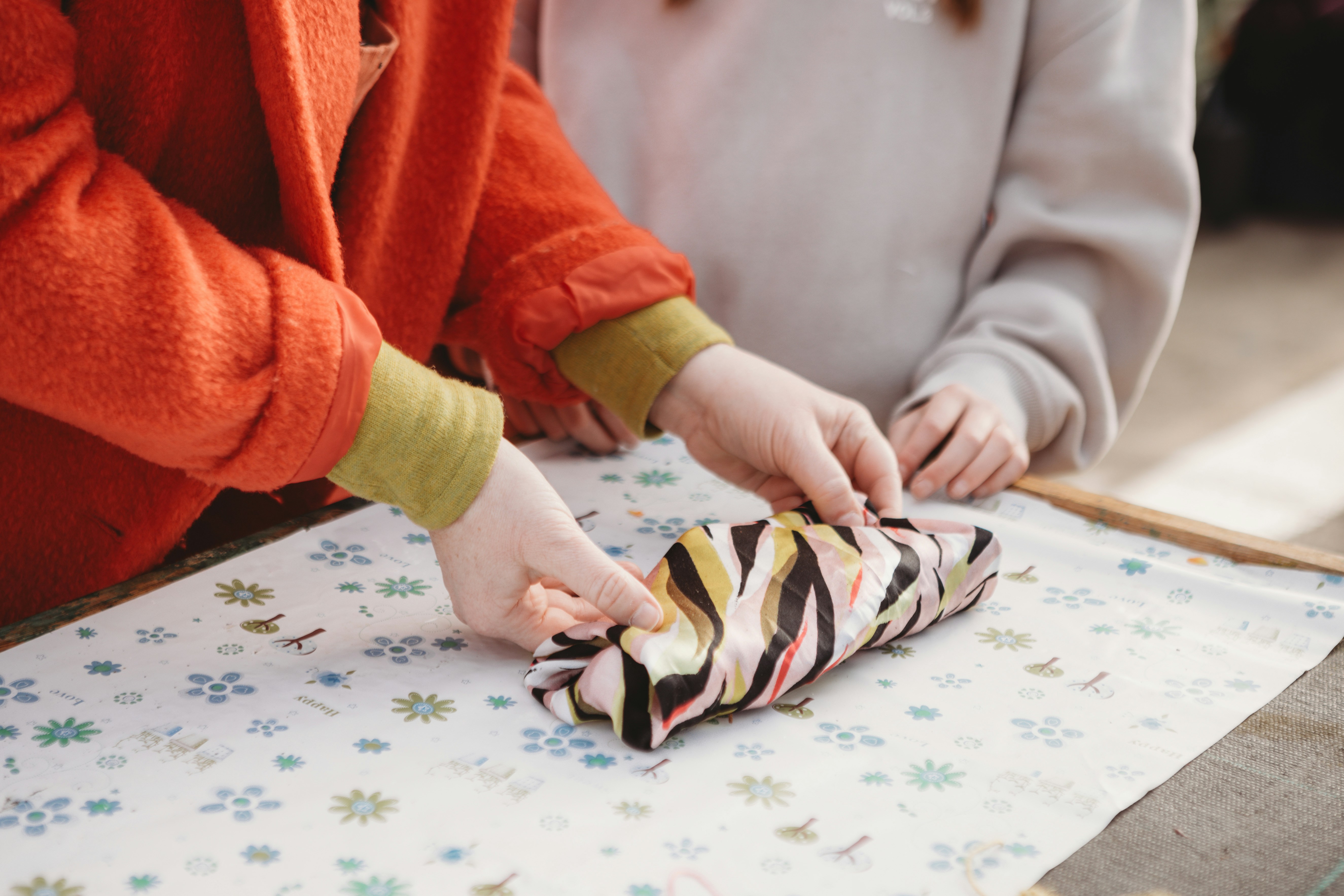 Hands wrapping an object in patterned fabric.
